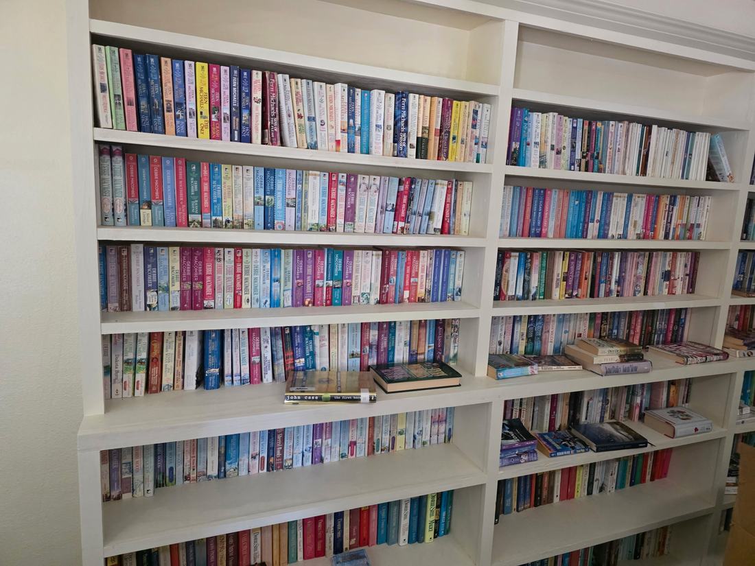 White built-in bookshelves packed with hundreds of paperback novels